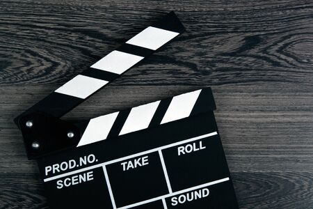 black movie clapper with white inscriptions on a wooden table top viewの写真素材