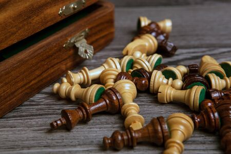 scattered chess pieces with chessboard on a wooden background close upの写真素材