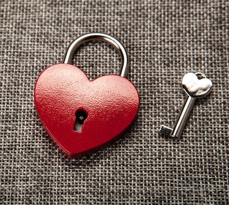 heart shaped padlock with a key on gray linen top viewの写真素材