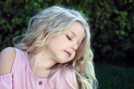 little girl in a pink dress on a green lawn portraitの写真素材