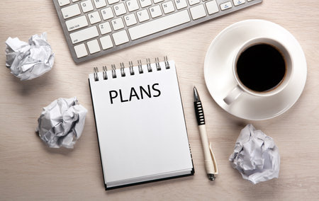 work table, a cup of coffee, a notebook with a pen and crumpled paper top viewの写真素材