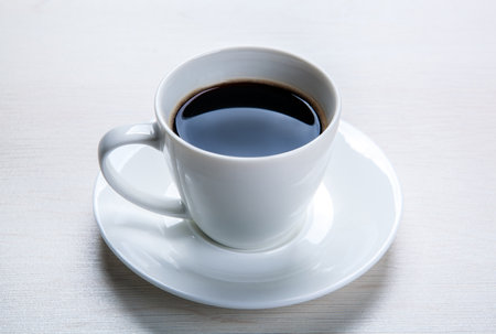 white cup with black coffee and saucer on the table closeupの写真素材