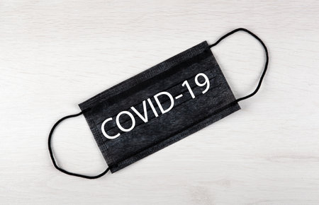 black medical mask with inscription covid-19 on the tableの写真素材