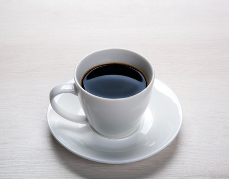 white cup with black coffee and saucer on the table closeupの写真素材