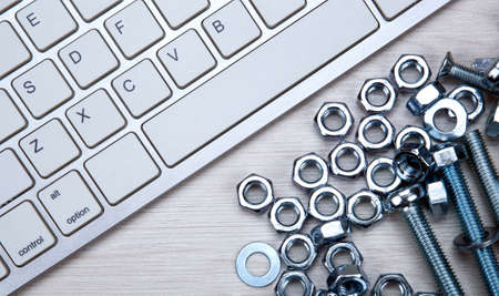 nuts screws fastening materials and pc keyboard on a wooden background top viewの写真素材