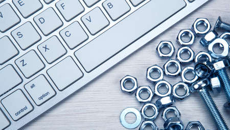 nuts screws fastening materials and pc keyboard on a wooden background top viewの写真素材