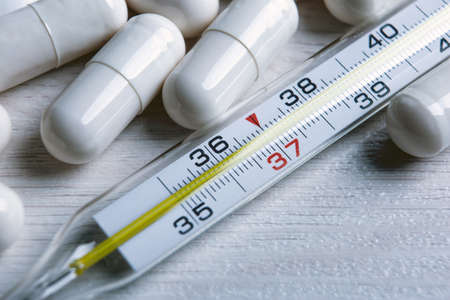 mercury medical thermometer and pills on the table closeup