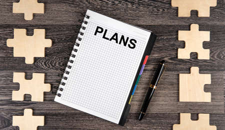 notepad with inscription plans with puzzle pieces with a pen top viewの写真素材
