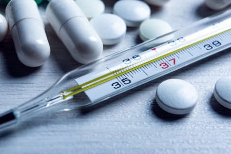 mercury medical thermometer and pills on the table closeupの写真素材