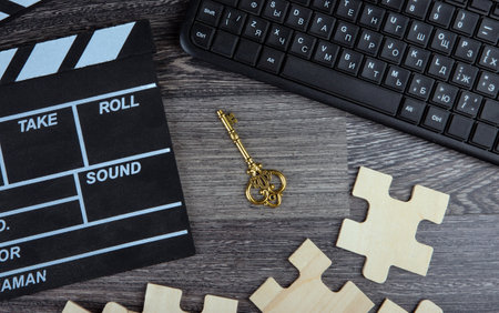 cinematic clapper, pc keyboard, golden key and puzzle pieces on a table top viewの写真素材