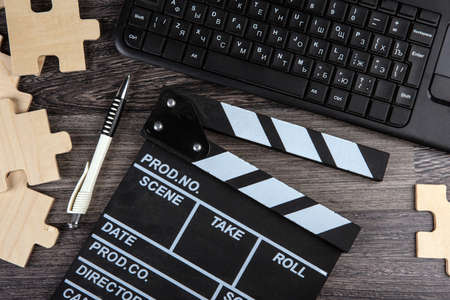 cinematic clapper, pc keyboard, pen and puzzle pieces on a table top viewの写真素材