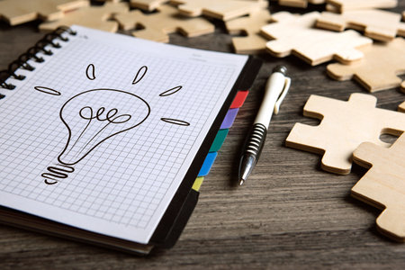 notepad with a pen and puzzle pieces and idea symbol closeupの写真素材