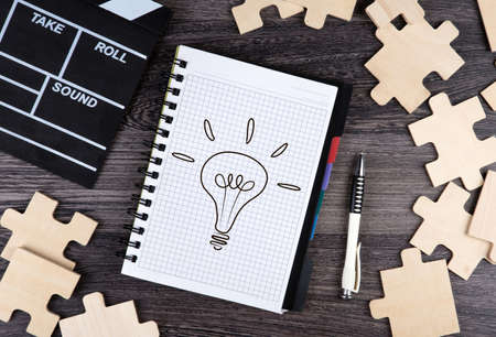 notepad with cinematic clapper, pen and puzzle pieces on a table top viewの写真素材