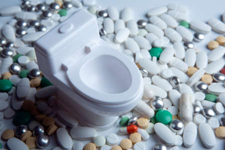 toilet bowl miniature and pills on the table closeupの写真素材