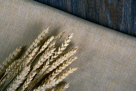 ears of wheat bouquet on sackcloth and wooden table top viewの写真素材