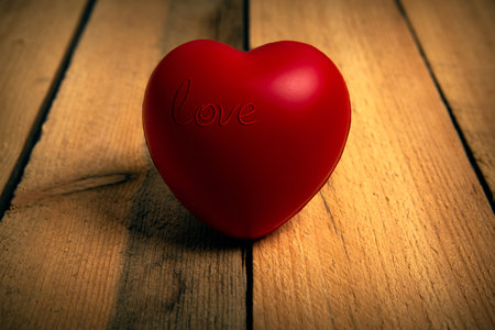 Large red heart with inscription love on wooden background close upの写真素材