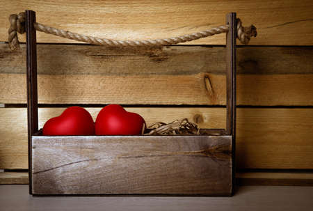 two large red hearts in the basket on a wooden backgroundの写真素材