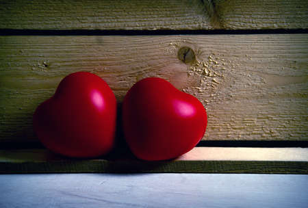two large red hearts on a wooden background close upの写真素材