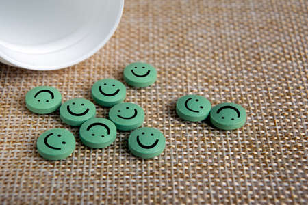 green round pills with emoticons poured out of a jar on a napkinの写真素材