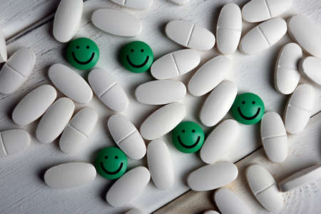 pills of antidepressant with emoticons on a wooden table top viewの写真素材