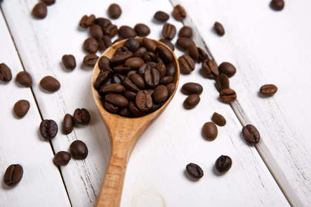 roasted coffee beans with wooden spoon on a white wooden backgroundの写真素材