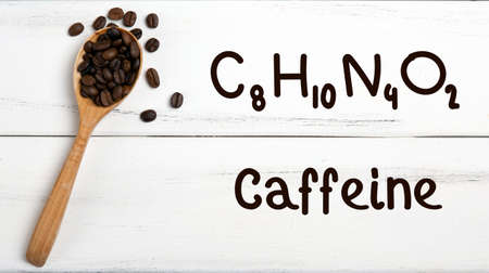 coffee beans with wooden spoon and chemical structure of caffeine on a wooden tableの写真素材