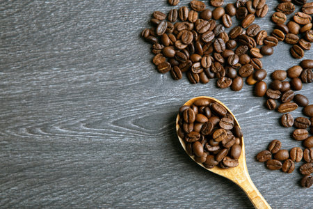 roasted coffee beans with wooden spoon on a wooden backgroundの写真素材