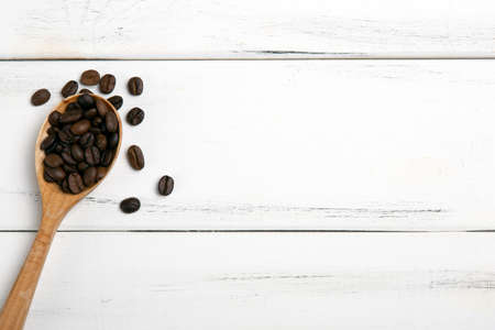 roasted coffee beans with wooden spoon on a white wooden backgroundの写真素材
