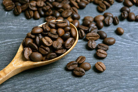 roasted coffee beans with wooden spoon on a wooden backgroundの写真素材