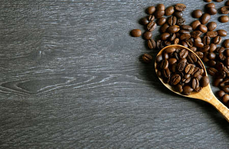 roasted coffee beans with wooden spoon on a wooden background