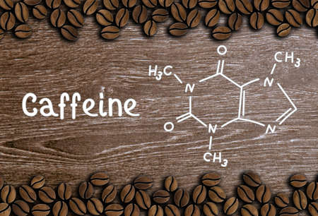 coffee beans with inscription and chemical structure of caffeine on a wooden backgroundの写真素材