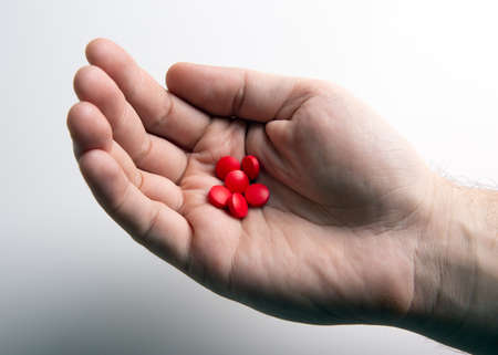 red pills in human hand on a gray table closeupの写真素材