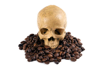 roasted coffee beans with a human skull as a symbol of danger closeupの写真素材