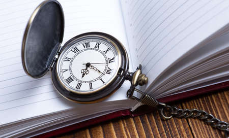 pocket watch with notepad on wooden background closeupの写真素材