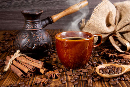 ceramic brown cup with black coffee and grains on wooden