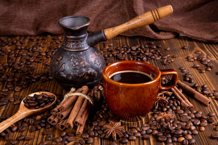 ceramic brown cup with black coffee and grains on woodenの写真素材