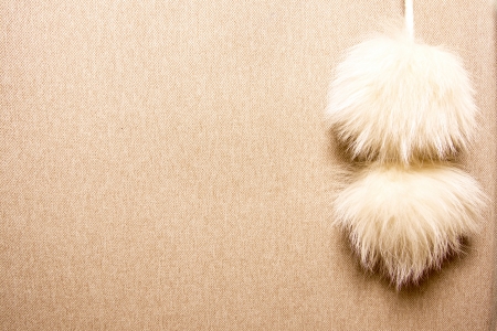 cashmere beige background with two blonde fur pomponsの写真素材