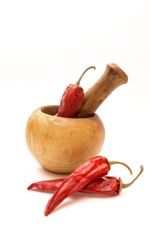 Dried red hot peppers with wooden mortar and pestle isolated on white. Selective focus.の写真素材