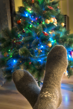 Winter evening. Feet in warm woolen socks around the Christmas tree. の写真素材