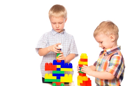 Beautiful happy smiling joyful children (little boys, brothers) playing and  building plastic construction (educational game)  isolated on white background.の写真素材