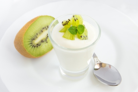 Fresh yogurt with kiwi (fruit) in glass beaker on white plate closeup, horizontal, copy spaceの写真素材