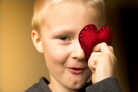 Happy cute child (kid, boy) with hand made red heart. Valentines day and family love concept. Horizontal close up portrait.の写真素材