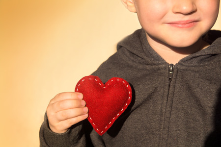 Red heart in child hands. Kindness concept, gift, hand made valentine, close up, horizontal, copy...