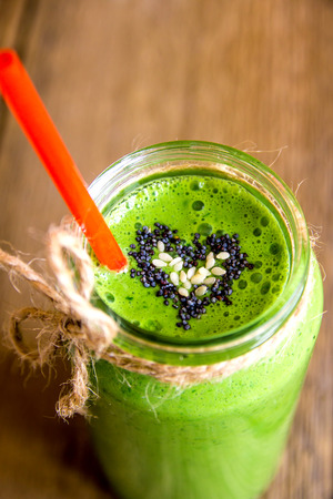 Green vegetable and herbs smoothie with heart of poppy and sesame seeds. Love for a healthy raw food concept.の写真素材