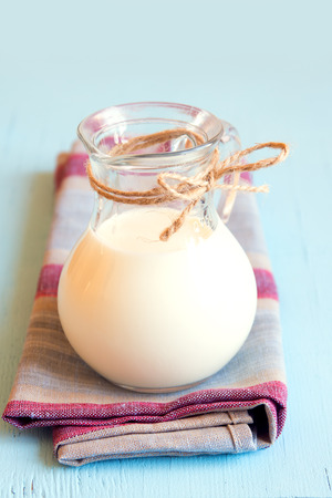 Milk in glass jar on naprin and blue wooden table, verticalの写真素材