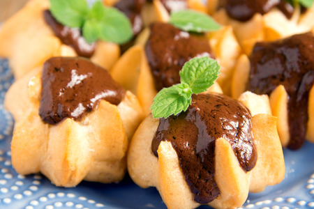 Profiteroles with chocolate sauce and mint on plate close upの写真素材