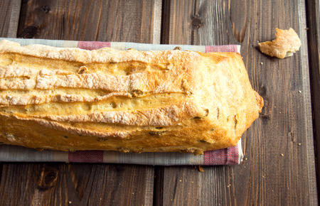 Fresh italian ciabatta bread with green olives on wooden table