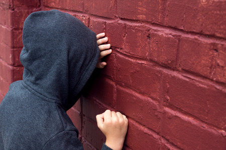 Worried depressed sad teen boy (child) crying near brick wallの写真素材