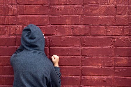 Worried depressed sad teen boy (child) crying near brick wallの写真素材
