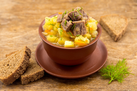Beef stew with potatoes in ceramic bowl over rustic wooden backgroundの写真素材
